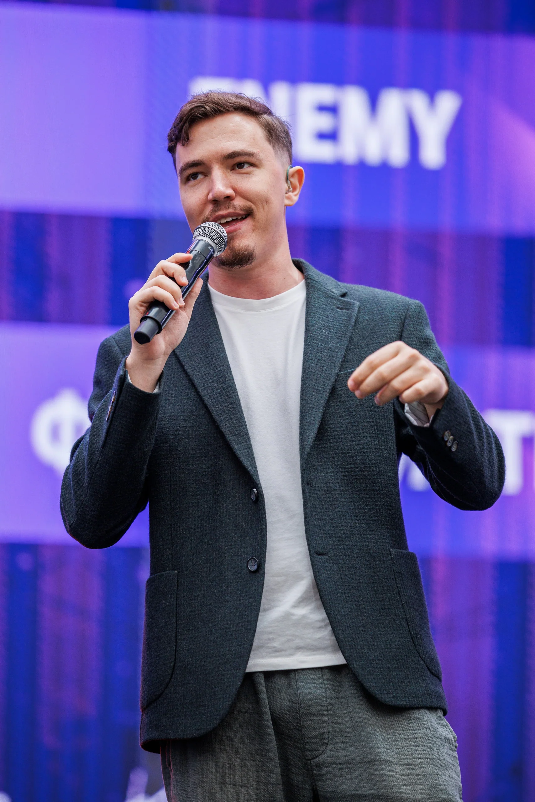 Dima Krupnov speaking into a microphone on a purple-lit stage